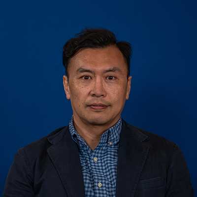 A Chinese man with short, dark hair smiling at the camera.