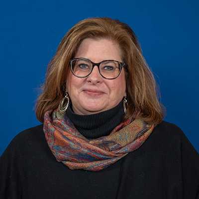 A woman with shoulder-length brown hair and glasses.