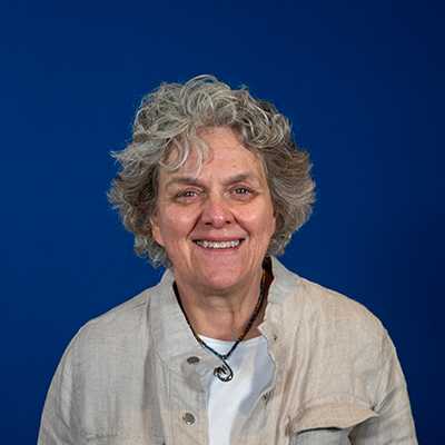 An older woman with short, curly, gray hair smiling at the camera.