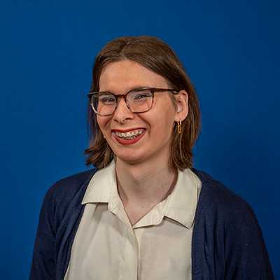 A young white woman in a white blouse and navy-blue cardigan.